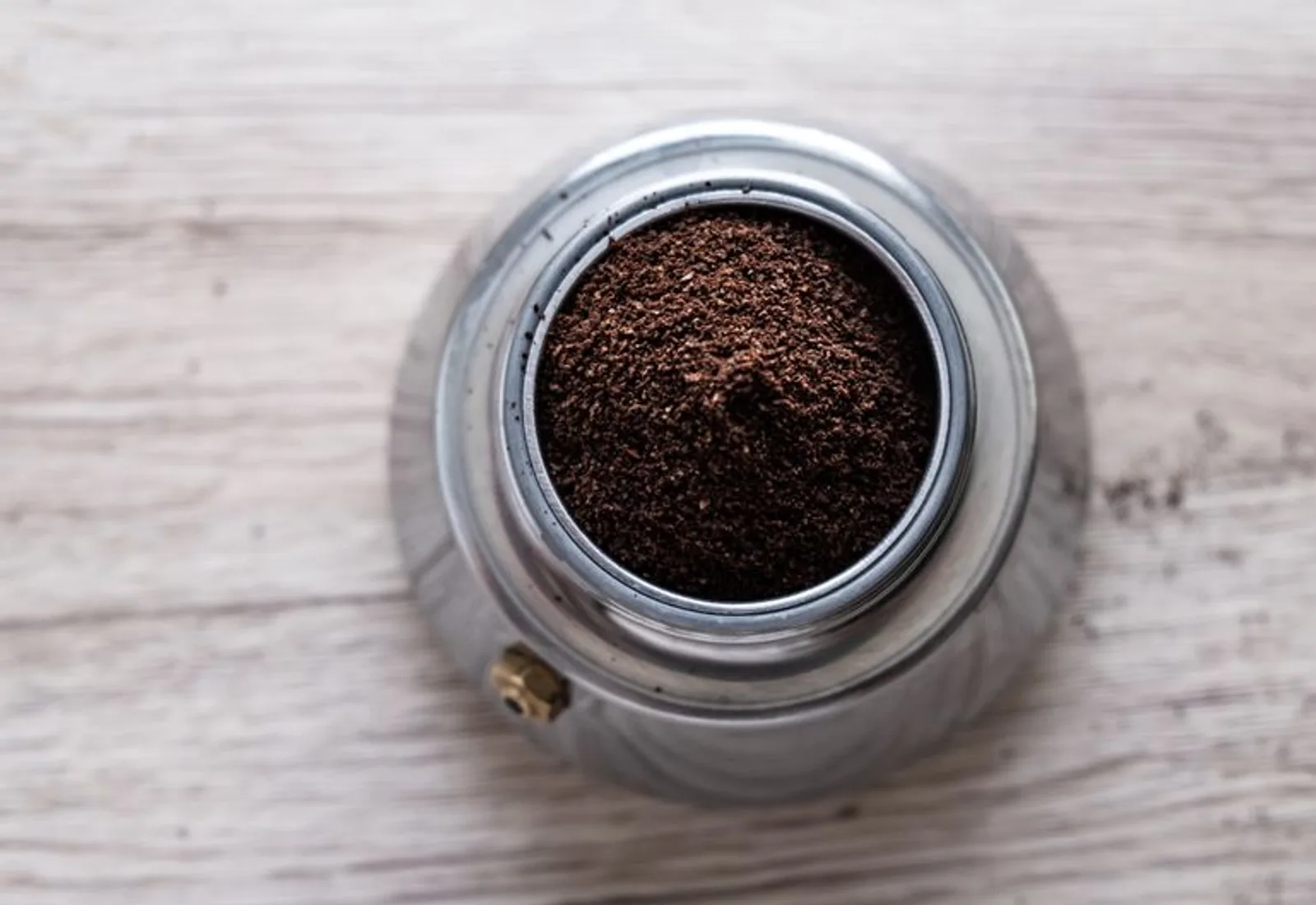 A portafilter basket of finely ground coffee seen from above