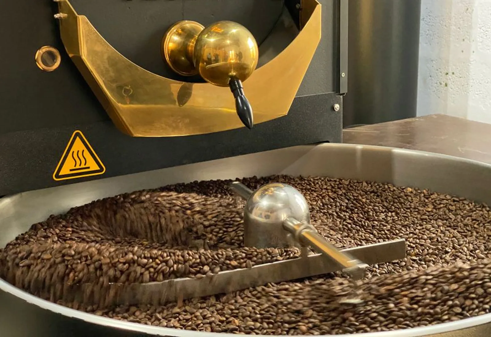 Beans tumbling in the drum of a roaster, glowing under the light