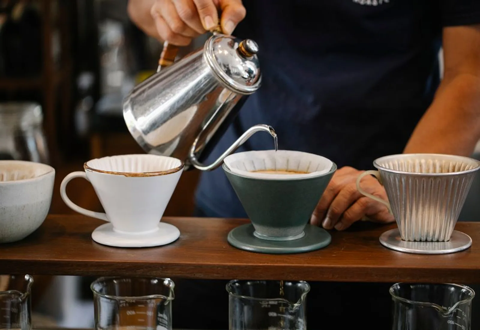 A gooseneck kettle pouring over a dripper as the bed blooms