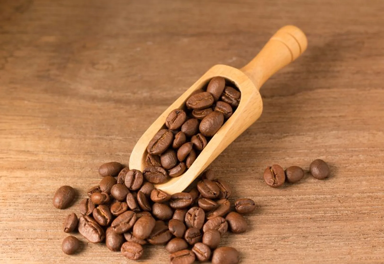 A scoop of medium-roast beans spilling onto a plain surface