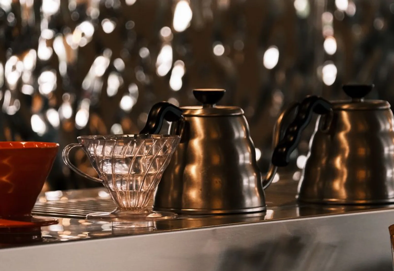 A row of matte gooseneck kettles lined up on a counter