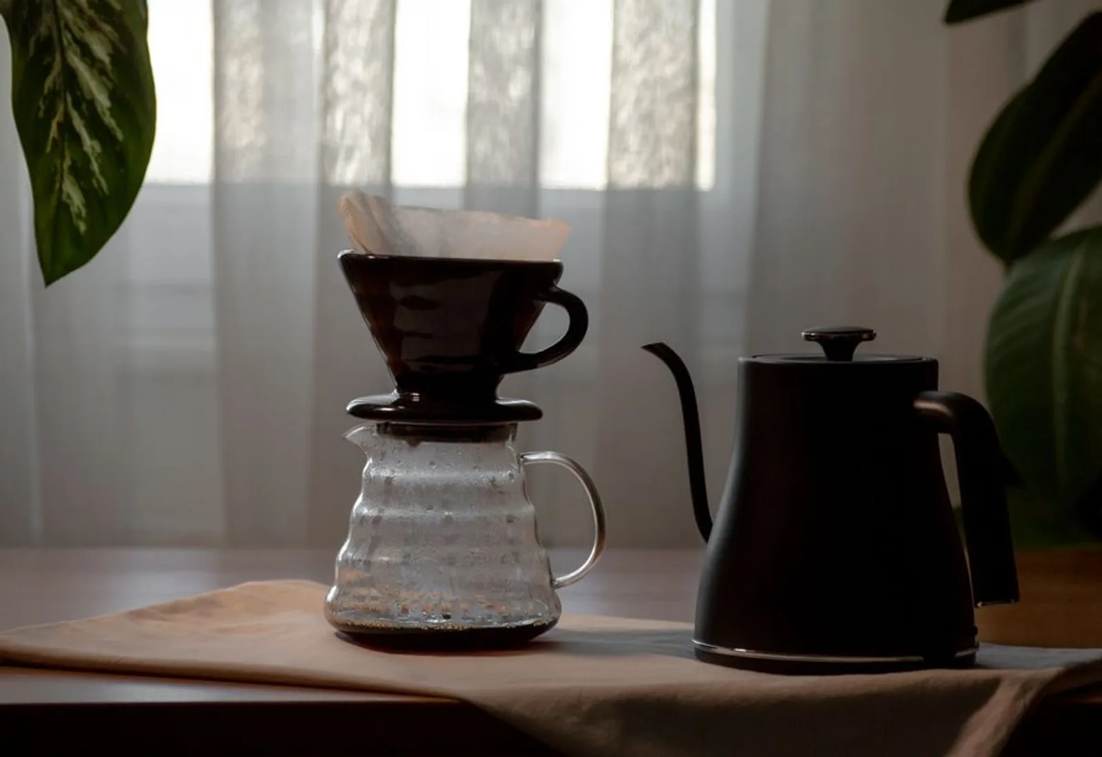 A ceramic pour-over cone and glass carafe on a bright bench